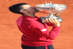 Novak Djokovic hält den French-Open-Pokal nach seinem Sieg gegen Rafael Nadal im Finale der Herren-Einzel, feiert mit einem triumphalen Ausdruck.