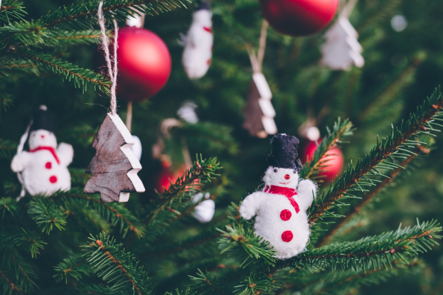 Ein Weihnachtsbaum geschmückt mit Schneemännern, bunten Kugeln und Spielzeug, verbreitet eine festliche Stimmung.