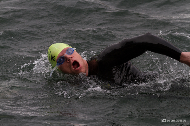 Ein Mann schwimmt im Wasser mit einer Mütze und Schwimmbrille.