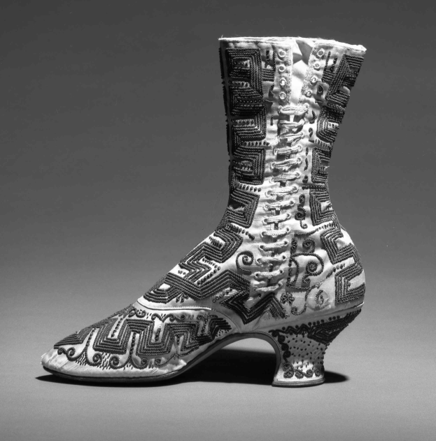Ein Paar hochhackige Stiefel mit farbenfroher, kunstvoller Stickerei in Blautönen, Grüntönen und Gelb.