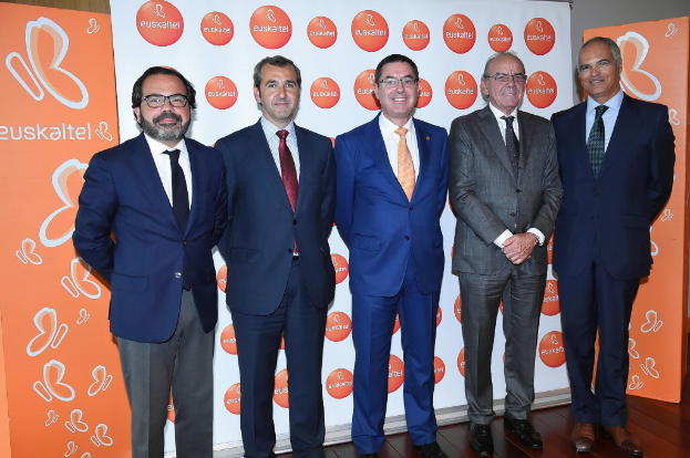 Eine Gruppe von M├Ąnnern, die f├╝r ein Foto posieren, mit Bannern im Hintergrund, die den Namen einer Organisation tragen.