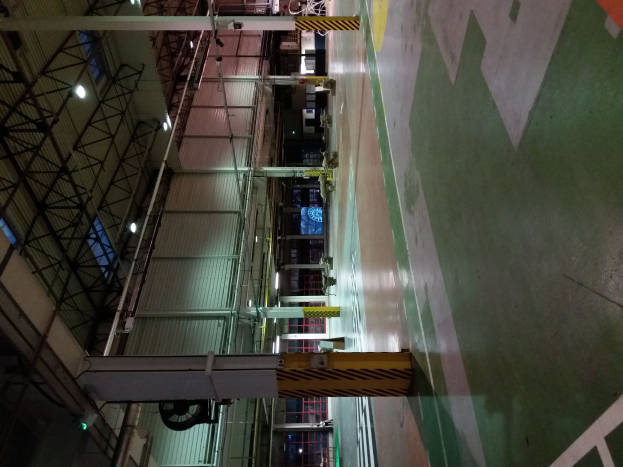 Ein großes Lager voller verschiedener Maschinen, Metallstangen, Lampen und anderer Gegenstände, mit lesbarem Text auf dem Boden auf der rechten Seite.