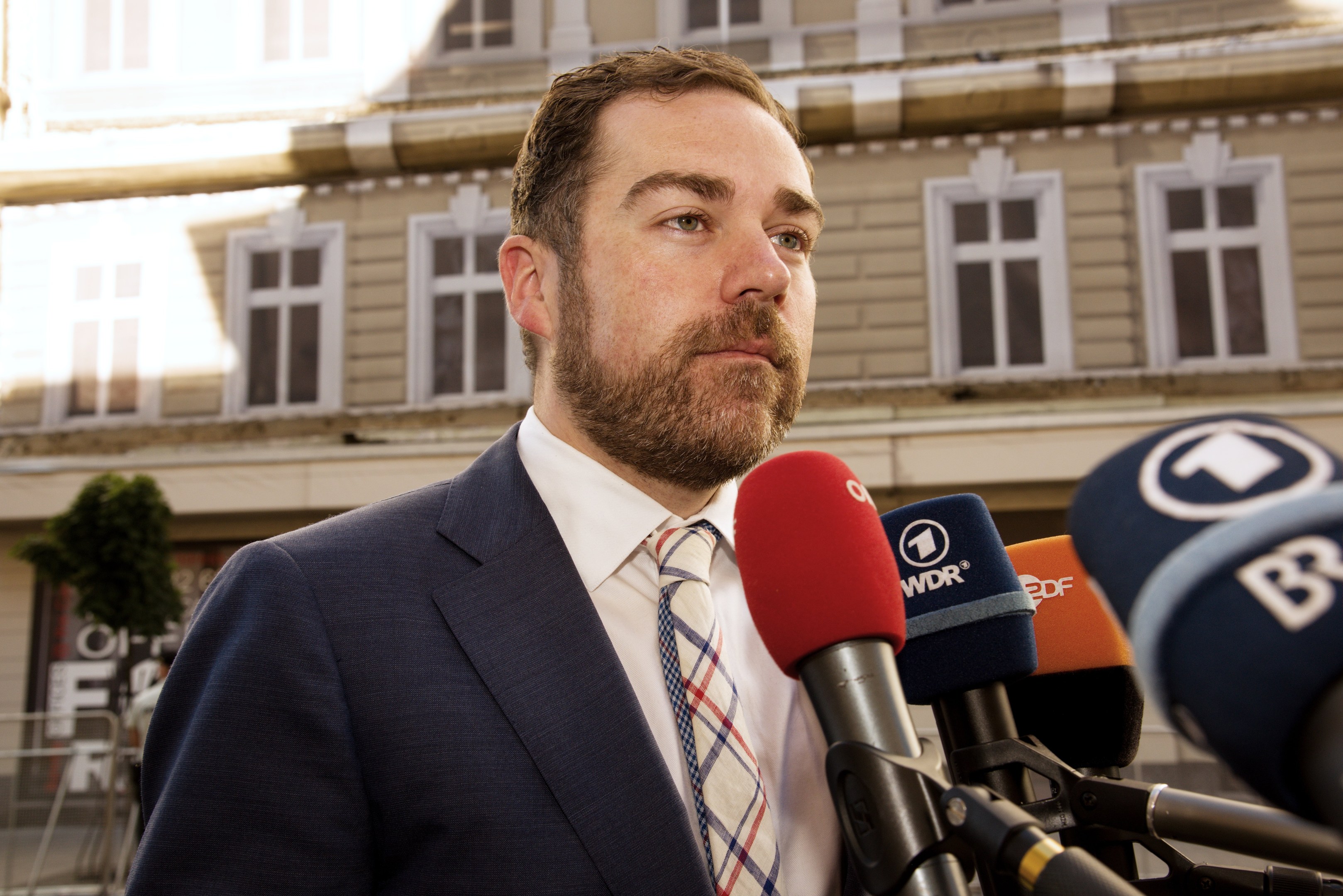 Ein Mann im Anzug spricht vor der Kamera, wahrscheinlich zu einer dreijährigen Haftstrafe.