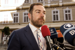 Ein Mann im Anzug spricht vor der Kamera, wahrscheinlich zu einer dreijährigen Haftstrafe.