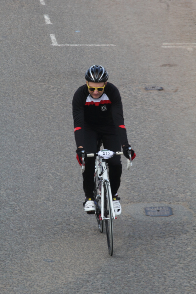 Eine Person mit Helm und Brille f√§hrt ein Fahrrad auf einer Stra√üe.