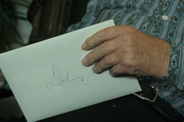 Eine Person sitzt und hält einen Brief in der Hand.