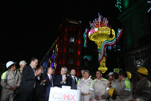 Eine Gruppe von Männern, einige mit Helmen, steht vor einem Gebäude und hält ein Schild mit der Aufschrift "Mexikanischer Präsident Andrés Manuel López Obrador eröffnet die neue CDMX-Zentrale in Mexiko-Stadt", mit anderen Gebäuden und dem Himmel im Hintergrund.