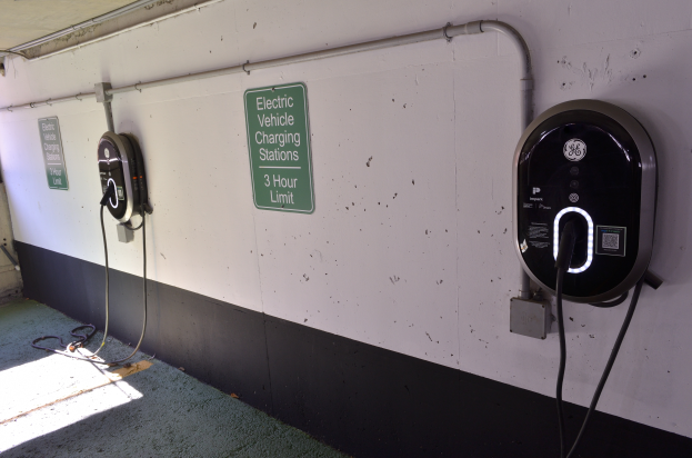 Eine Elektrofahrzeug-Ladestation in einer Tiefgarage mit zwei an der Wand angebrachten Ladepunkten und Tafeln mit Text darauf, der Boden ist unten im Bild sichtbar.
