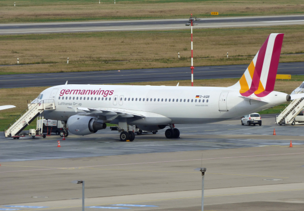 Germanwings Airbus A320-200 auf dem Frankfurter Airport mit Bodenfahrzeugen, Verkehrskegeln, Versorgungsmasten und Grünfläche im Hintergrund.