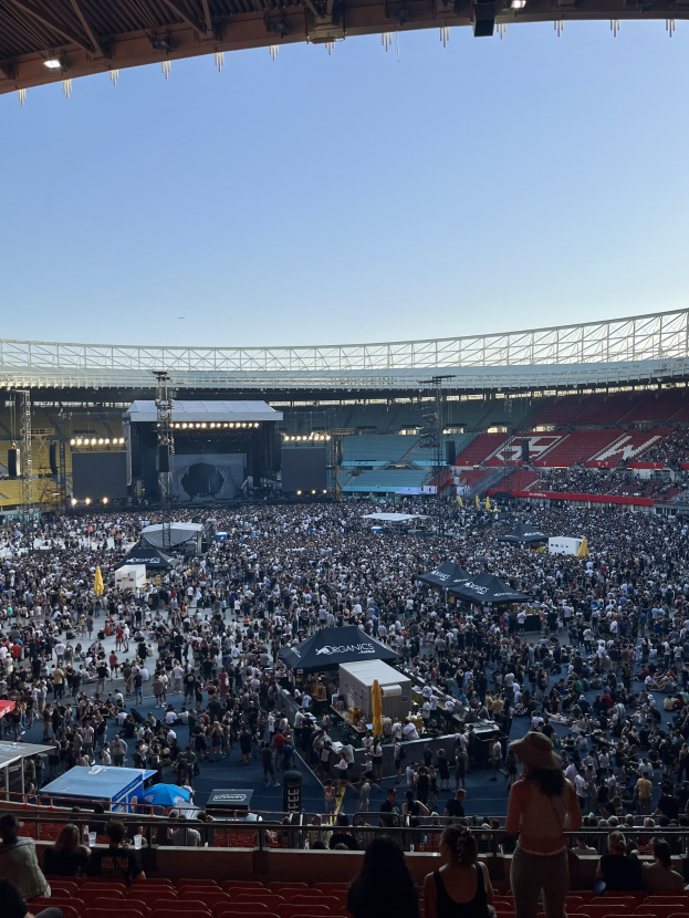 Große Menschenmenge auf Sitzplätzen und Stehplätzen in einem Stadion mit Zelten, Geländern und Beleuchtung bei einem Event in der O2 Arena in London.