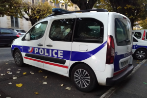 Ein Polizeiwagen parkt auf einer Straße mit Gebäuden, Bäumen und heruntergefallenen Blättern.