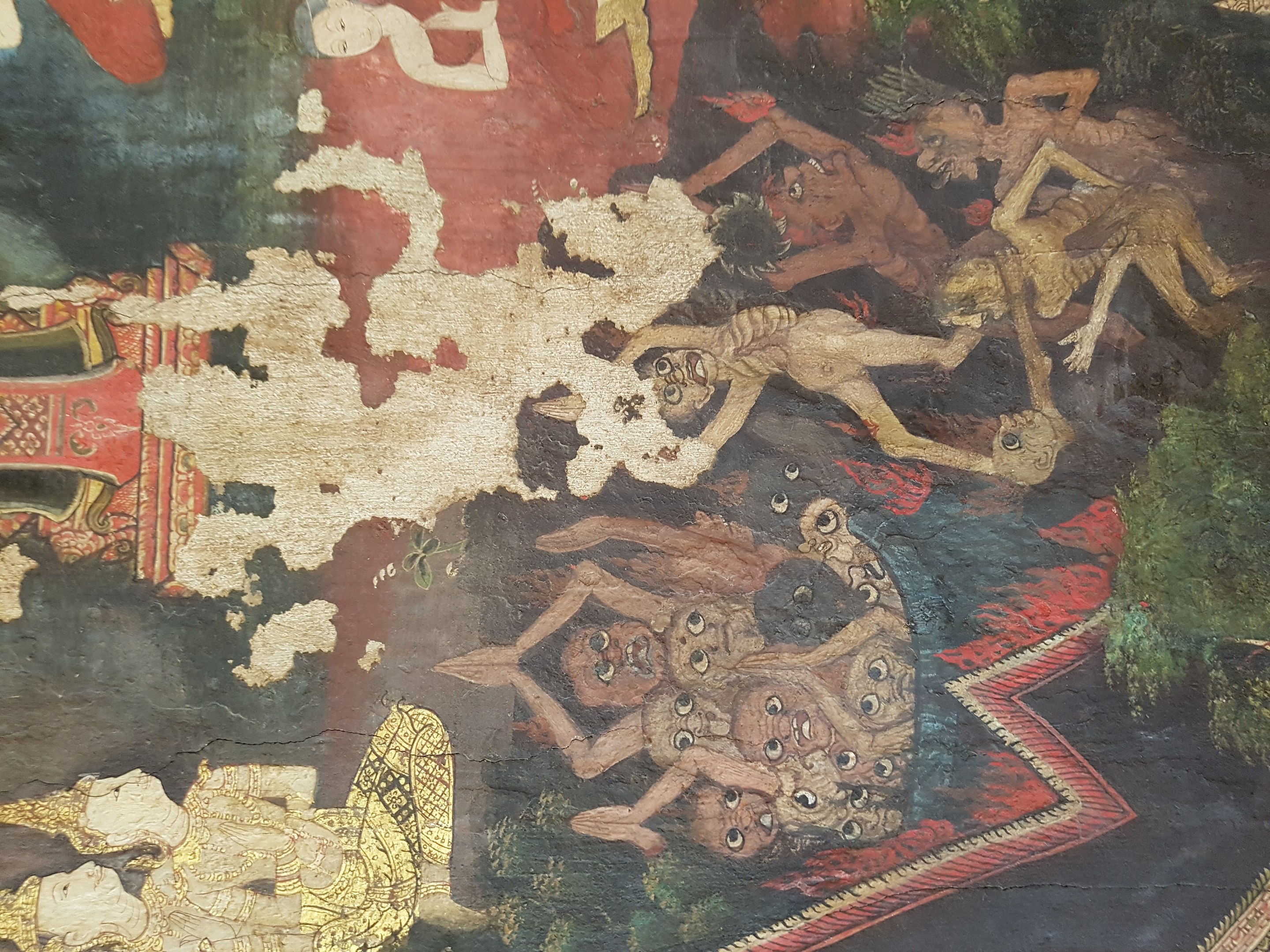 Ein farbenfrohes Wandgemälde in einem thailändischen buddhistischen Tempel zeigt Menschen in traditioneller Kleidung neben einem Löwen, Giraffe, Affe und Zebra in einer grünen Landschaft mit Bäumen und fernen Bergen.