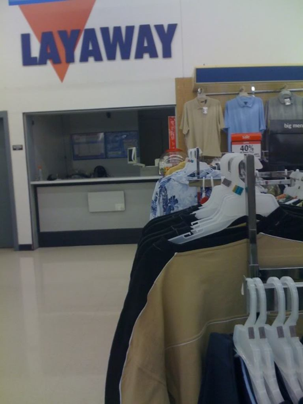 Ein Innenblick in ein Geschäft mit Kleiderbügeln, einem Tisch und einer Preistafel.