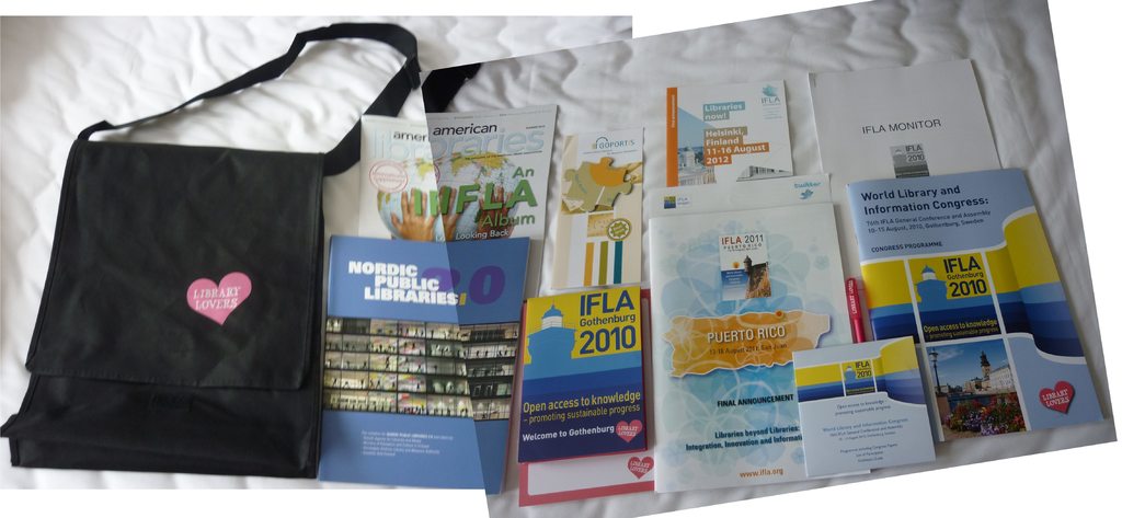 Eine Tasche mit der Aufschrift 'Bibliotheksliebhaber' und einige Bücher auf einem Bett.