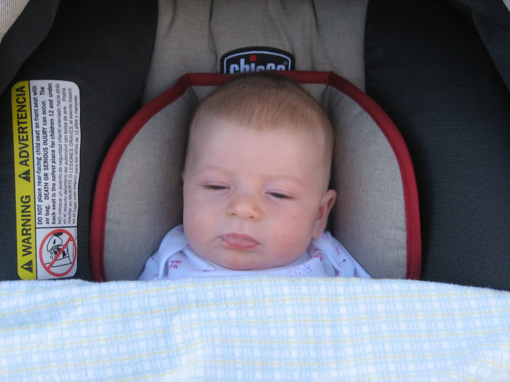 Ein Baby unter einer Babyliege mit einem Warnaufkleber auf der linken Seite.