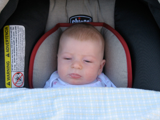 Ein Baby unter einer Babyliege mit einem Warnaufkleber auf der linken Seite.