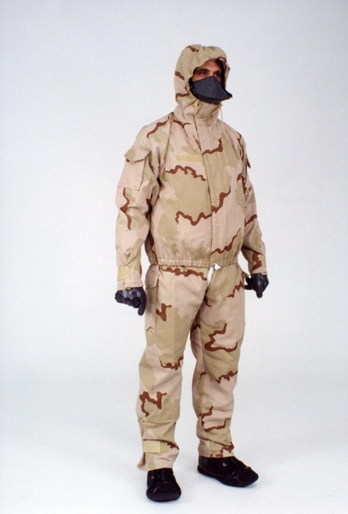 Mann in einem Tarnmuster-Schutzoverall mit Kapuze und Maske, der vor einem weißen Hintergrund steht.
