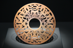 Ein chinesischer geschnitzter Jade-Teller in einem Museum ausgestellt, mit detaillierten Oberflächenverzierungen und einem dunklen Hintergrund.