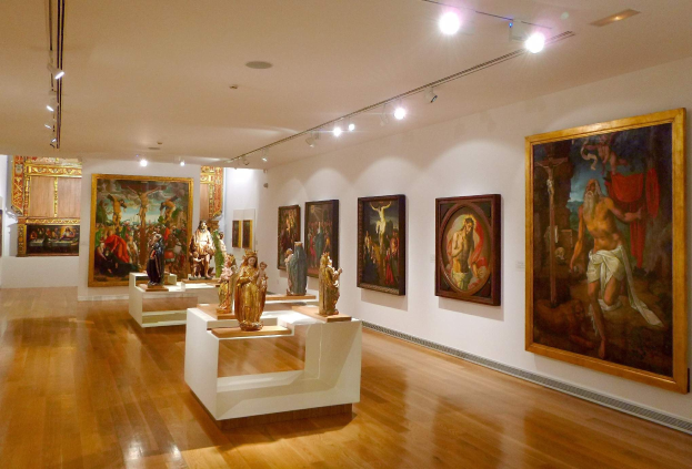 Ein großer Raum im Metropolitan Museum of Art in New York City zeigt zahlreiche Gemälde an den Wänden, Skulpturen auf Tischen und Deckenleuchten.