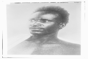 Ein Schwarz-Weiß-Foto eines Mannes mit ernstem Gesichtsausdruck, mit dem Text "Seneg Verletzter französischer Gefangener Unter der Deutschen" oben.