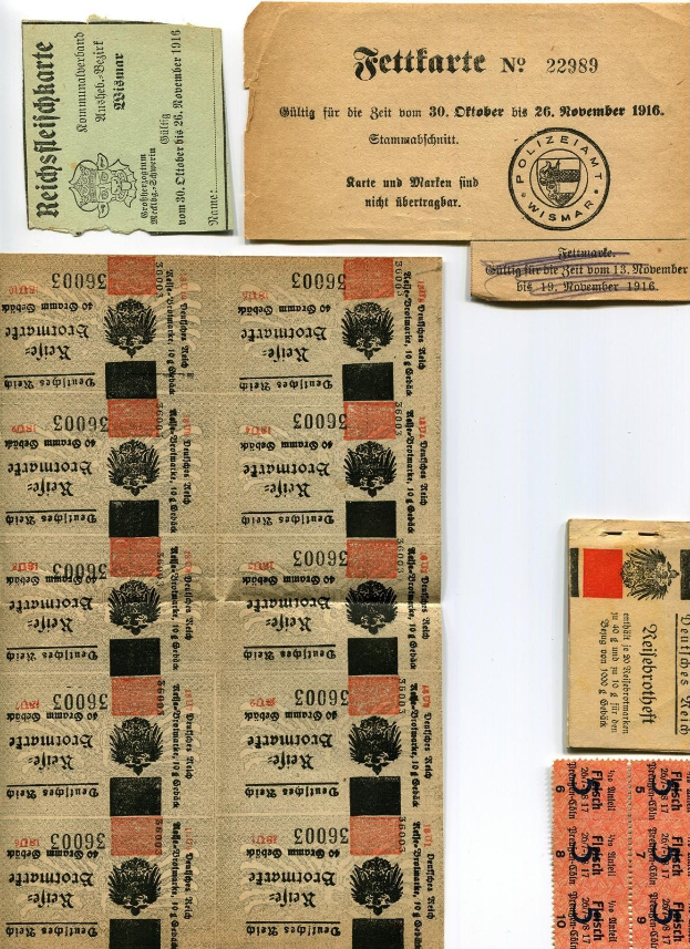 Sammlung alter deutscher Tickets und Marken auf weißem Hintergrund, die Abnutzungsspuren aufweisen und bedruckte Texte und Zahlen enthalten.