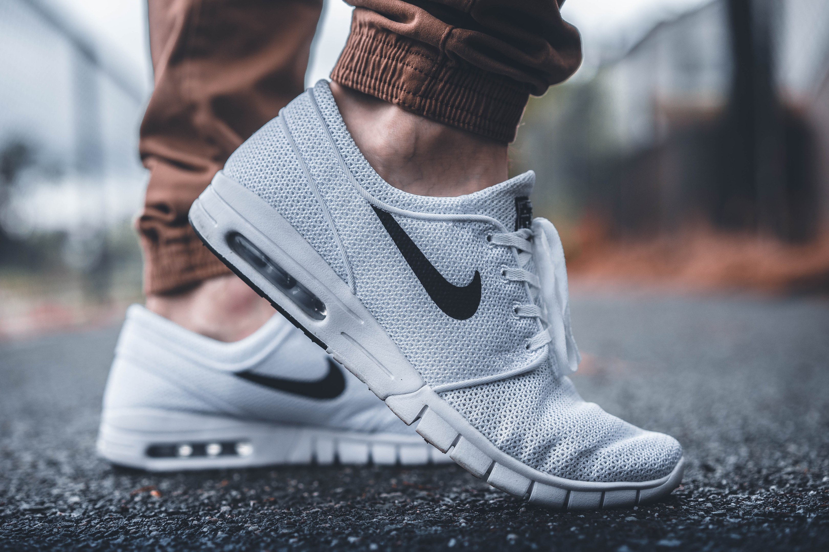 Eine Person in Nike SB Stefan Janoski Max-Schuhen in Wolf Grau/Schwarz-Weiß mit einem unscharfen, träumerischen Hintergrund.