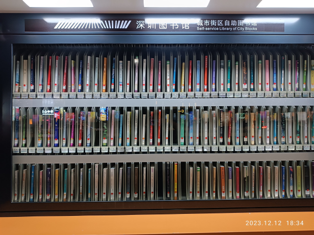 Eine gut beleuchtete Bibliothek mit hohen Regalen voller Bücher, mit einer Texttafel und einem Wasserzeichen unten.