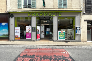 Eine Apotheke an der Straßenecke mit Glaswänden und -türen, Plakate an den Wänden und einer Straße davor.
