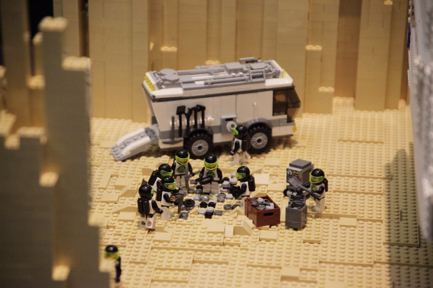 Lego-Modell einer Star-Wars-Szene mit einem Fahrzeug im Vordergrund und einer Wand im Hintergrund sowie einigen verstreuten Spielzeugfiguren.