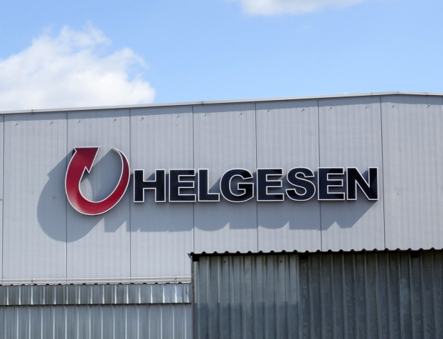 Helgesen sign on a building exterior with text reading "Helgesen investiert 1,5 Milliarden USD in den USA" gegen einen bewölkten Himmel.
