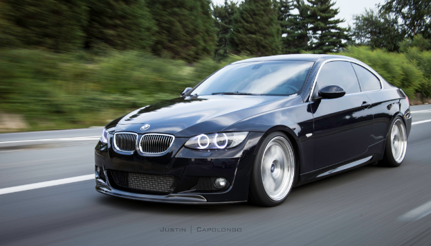 Ein schwarzer BMW auf einer Straße mit Bäumen im Hintergrund.