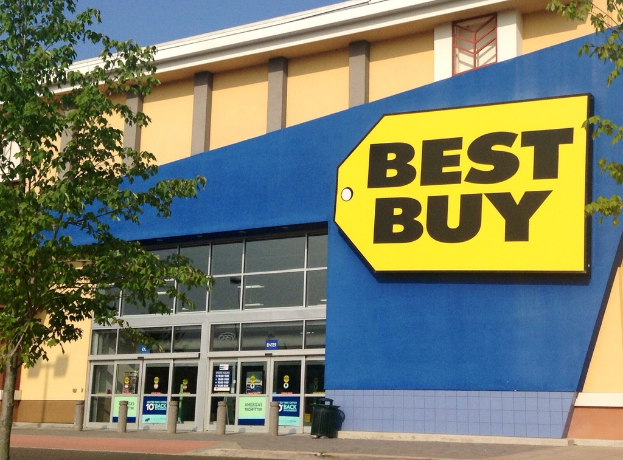 Ein Best Buy-Geschäftsgebäude mit einer sichtbaren Eingangstür und mehreren Bäumen draußen.