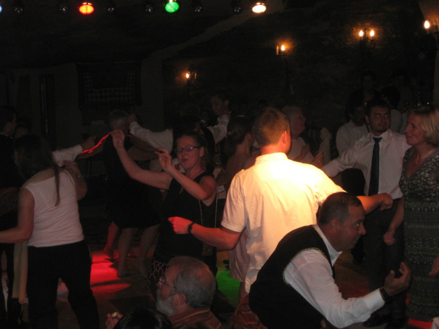Eine lebendige Partyszene mit tanzenden Menschen auf dem Boden unter einer dunklen Decke, die mit verschiedenen bunten Lichtern geschmückt ist.