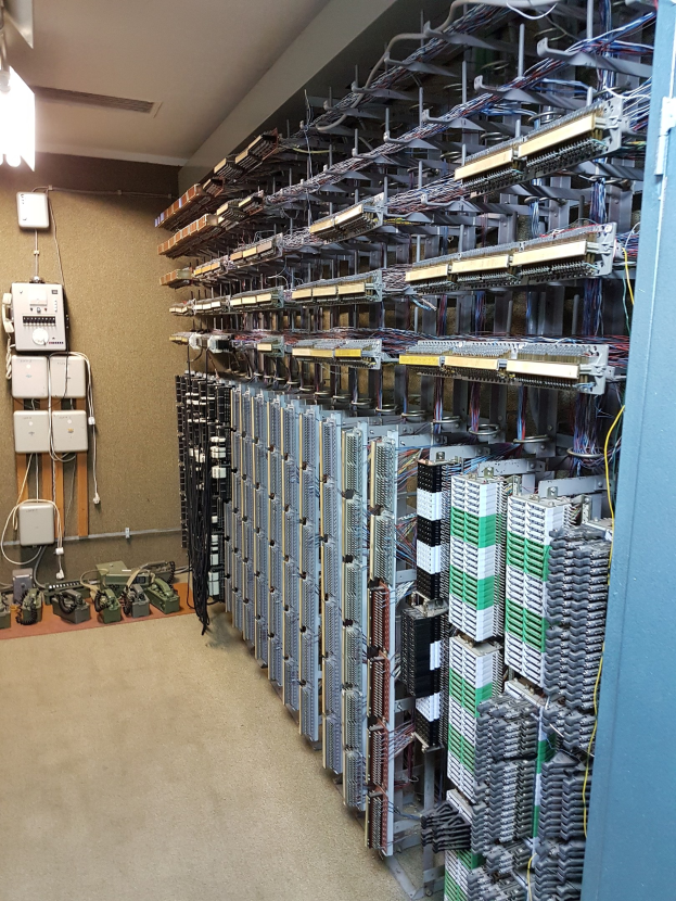 Großer Raum voller Numerous wires, elektronische Geräte und Server auf dem Boden, was auf eine Rechenzentrumseinrichtung hinweist.