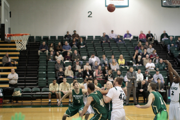 Ein Basketballfeld mit aktiv spielenden Spielern und Zuschauern im Hintergrund