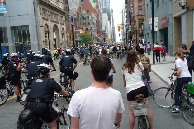 Mehrere Gebäude mit wenigen Menschen auf Fahrrädern auf einer Straße davor.
